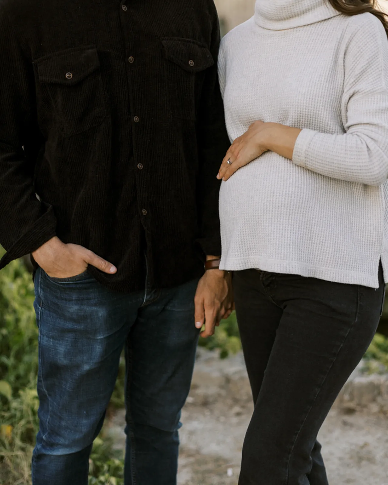 Expecting couple, hands resting on pregnant belly, warm natural light
